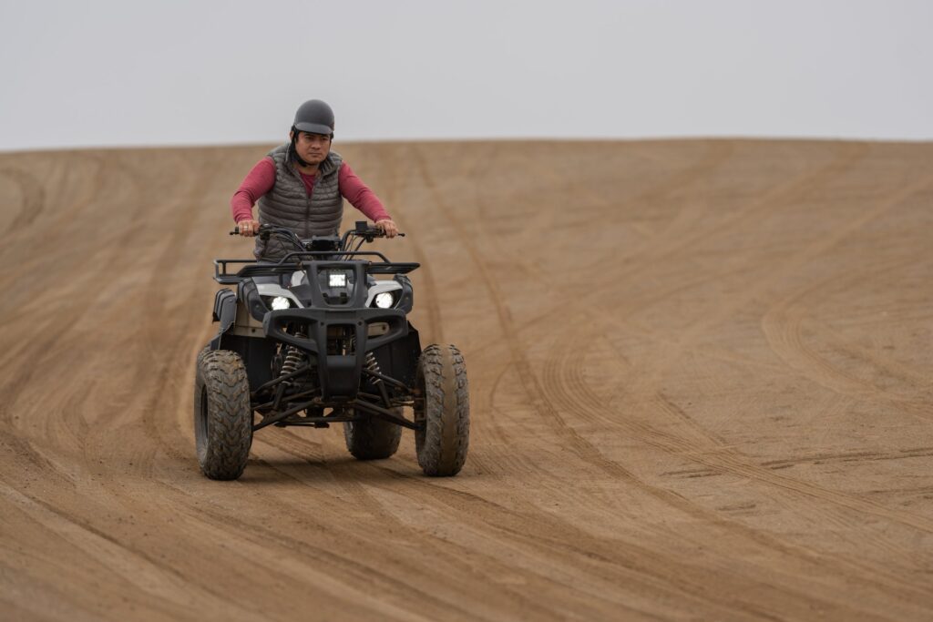 man driving a quad bike in a sandy terrain